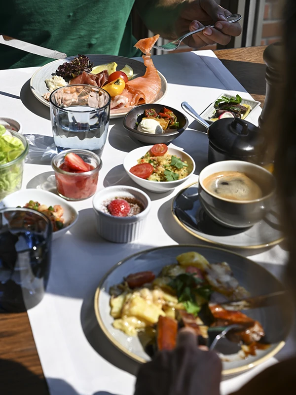Tisch mit Tellern und Schalen mit frischem Obst, Aufschnitt und Salat.